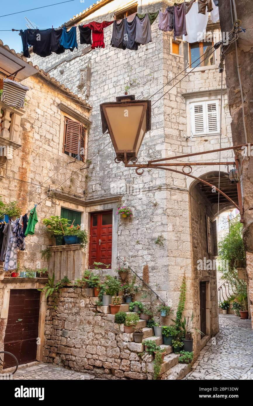 Rue pittoresque et étroite de la ville de Trogir avec pots de fleurs et sèche linge Banque D'Images
