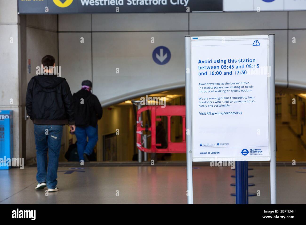 2020 mai : les travailleurs essentiels marchent devant des affiches d'information sur la santé publique à la station de métro Stratford, dans l'est de Londres Banque D'Images