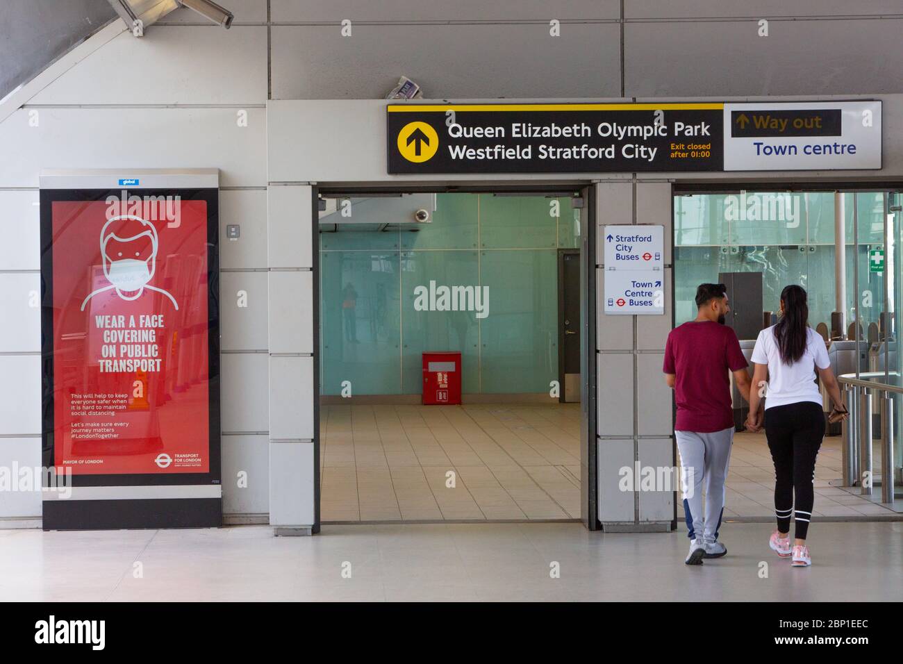 2020 mai : les travailleurs essentiels marchent devant des affiches d'information sur la santé publique à la station de métro Stratford, dans l'est de Londres Banque D'Images