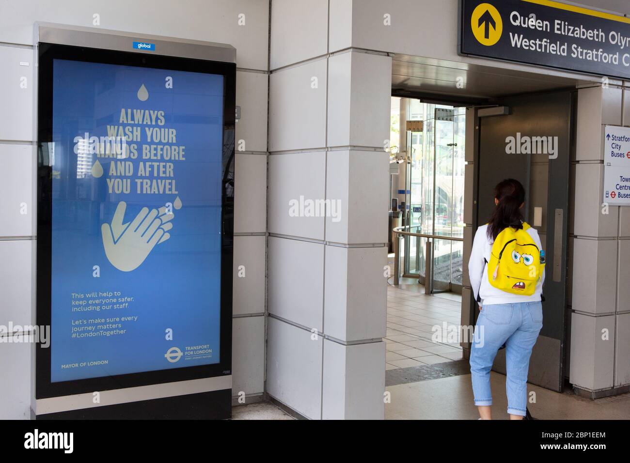 2020 mai : les travailleurs essentiels marchent devant des affiches d'information sur la santé publique à la station de métro Stratford, dans l'est de Londres Banque D'Images