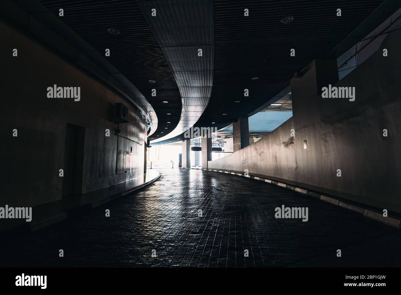 Sortez à la lumière du tunnel souterrain sombre dans le parking du centre commercial. Banque D'Images