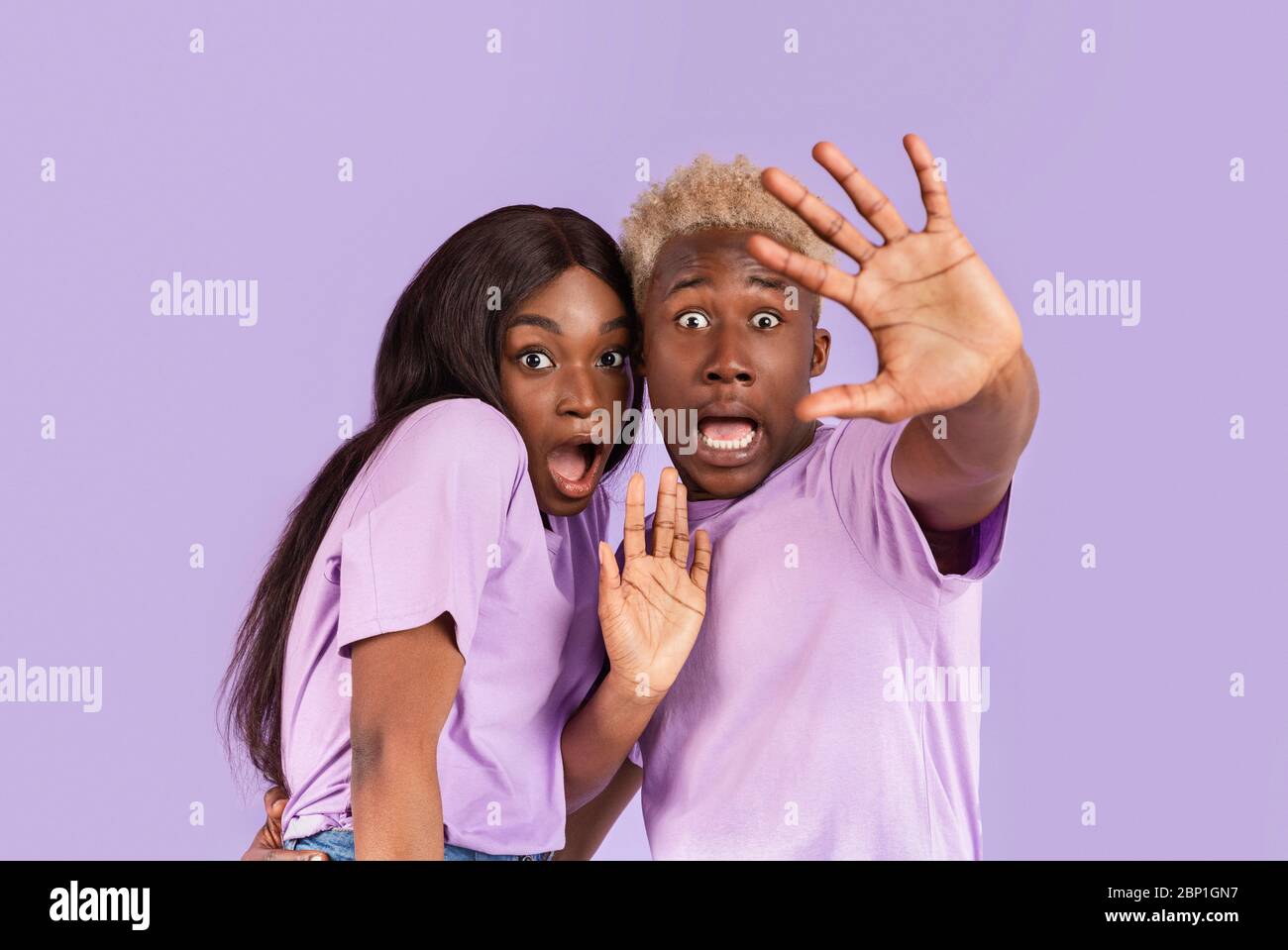 Portrait d'un couple noir avec des visages effrayés ou choqués sur fond lilas Banque D'Images