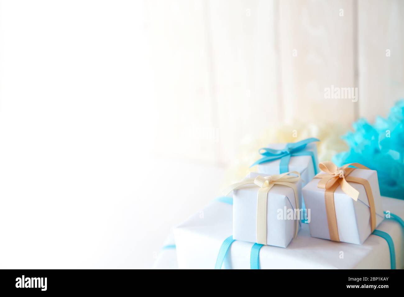 Boîte cadeau blanche avec rubans bleus, jaunes et beiges sur fond blanc. Banque D'Images