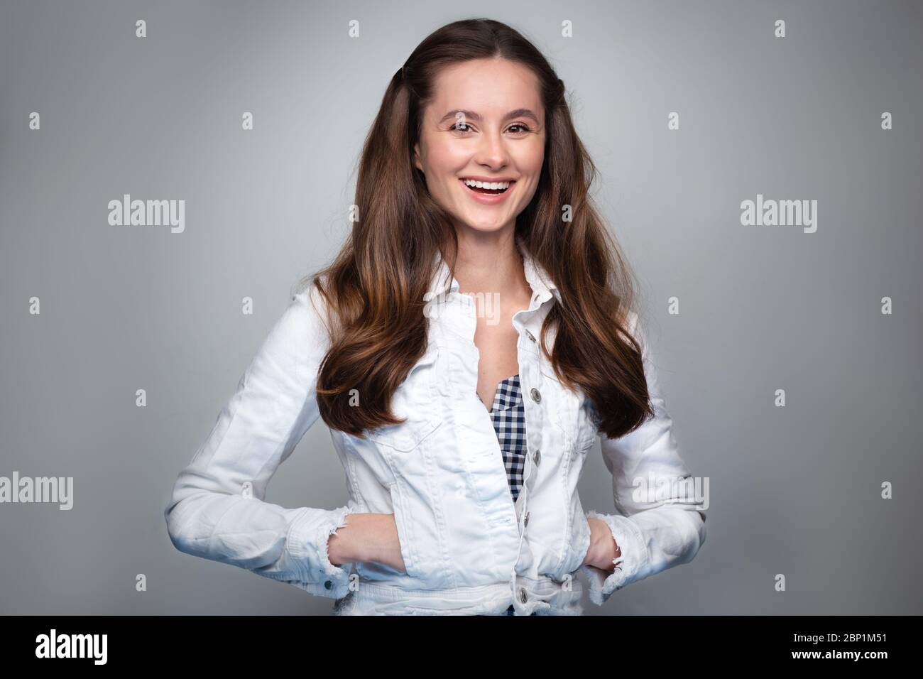 Gros plan d'une jeune femme élégante souriante sur fond gris. Banque D'Images