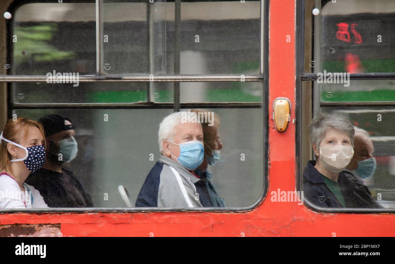 Belgrade, Serbie - 15 mai 2020 : personnes portant un masque chirurgical tout en étant assis et en conduisant dans un siège de fenêtre d'un tramway, de l'extérieur Banque D'Images