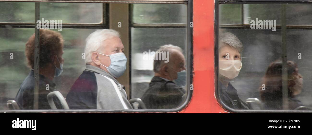 Belgrade, Serbie - 15 mai 2020 : personnes portant un masque chirurgical tout en étant assis et en conduisant dans un siège de fenêtre d'un tramway, de l'extérieur Banque D'Images