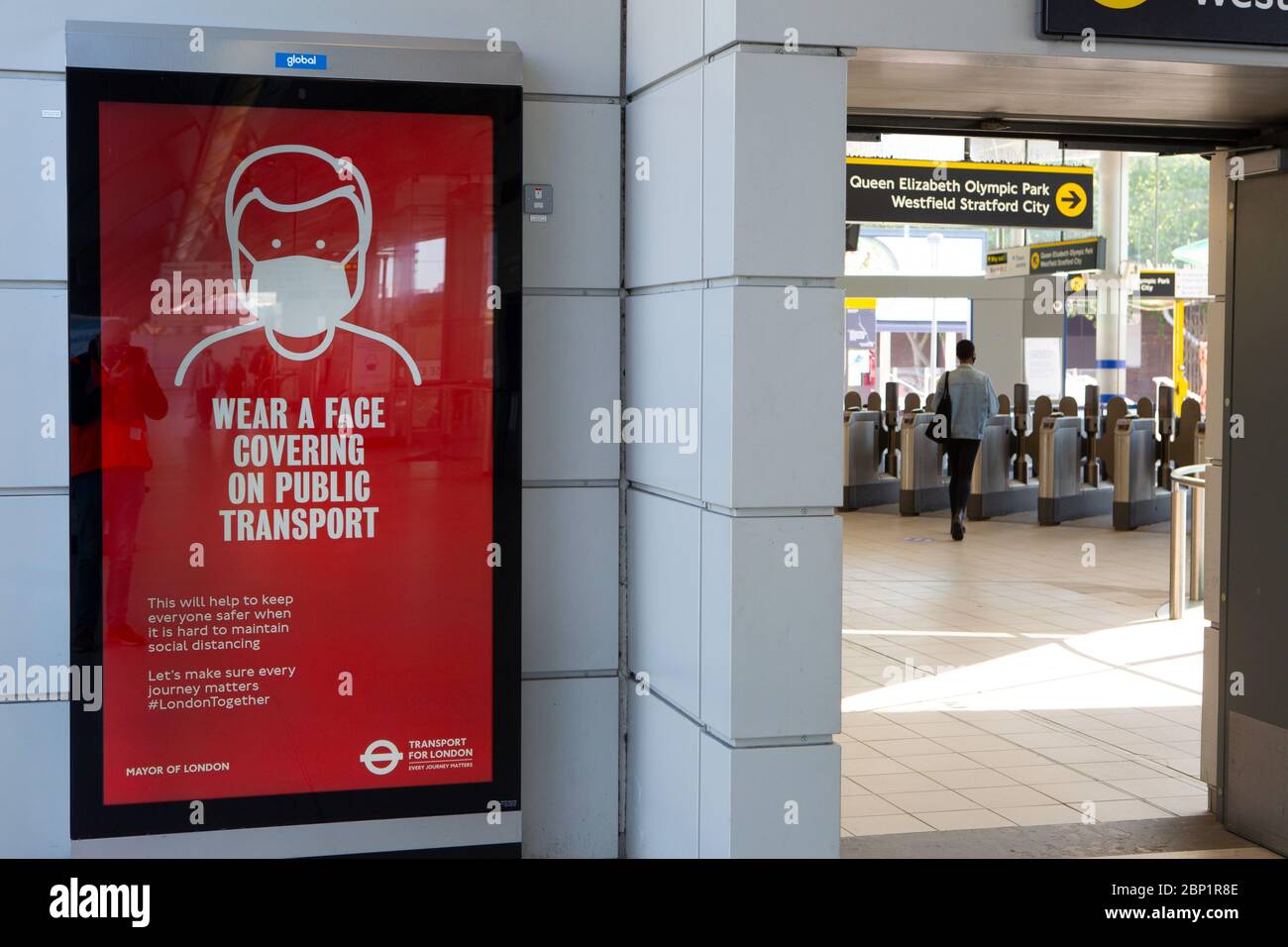 2020 mai : les travailleurs essentiels marchent devant des affiches d'information sur la santé publique à la station de métro Stratford, dans l'est de Londres Banque D'Images