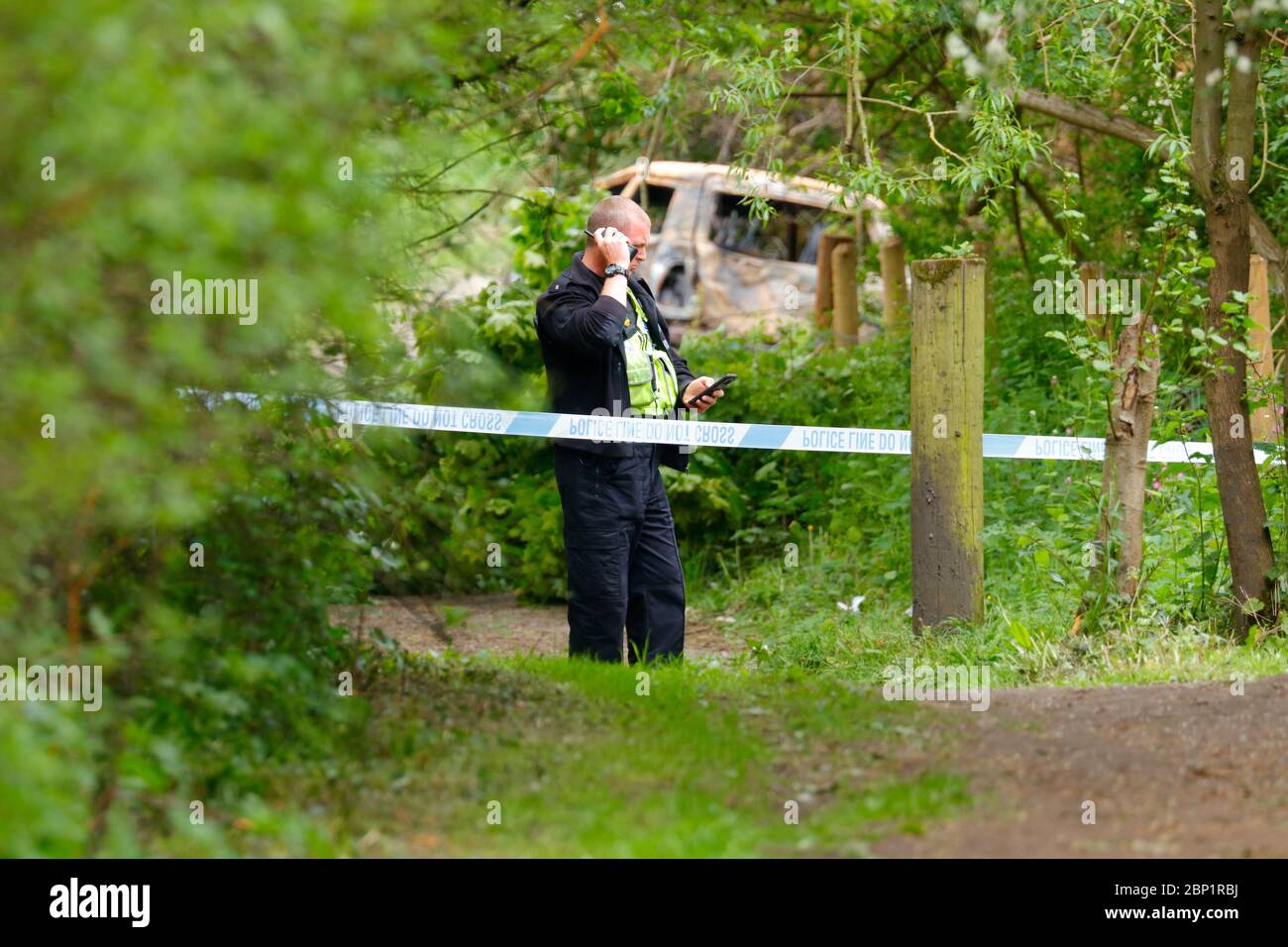 Une scène d'agent de crime garde un véhicule brûlé à Swillington, où le conducteur de la collision le véhicule a fui la scène. Banque D'Images