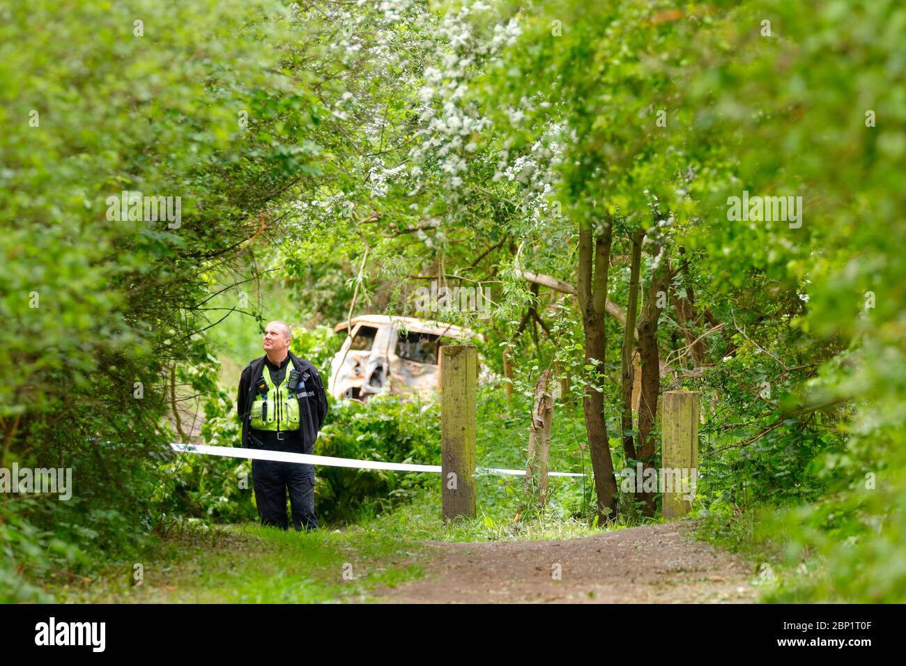 Une scène d'agent de crime garde un véhicule brûlé à Swillington, où le conducteur de la collision le véhicule a fui la scène. Banque D'Images