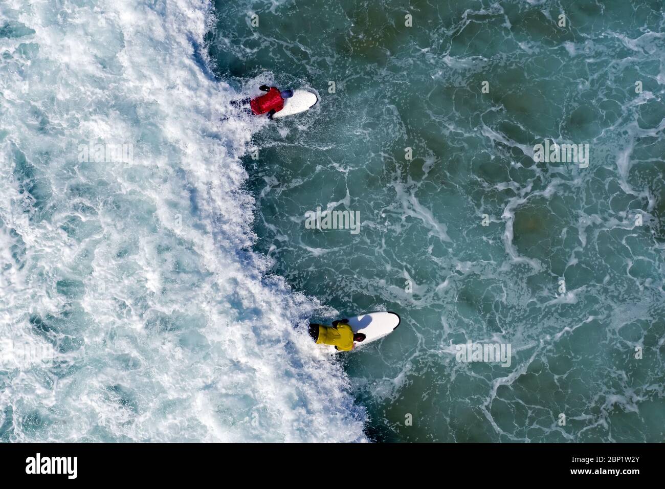 Photo aérienne des surfeurs essayant de prendre une vague dans l'océan Banque D'Images