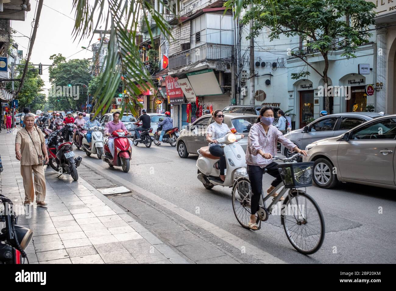 Hanoï, Vietnam - 30 avril 2018 : scène de rue avec les habitants qui débardent leurs vélos ou leurs motos dans une rue animée. Banque D'Images