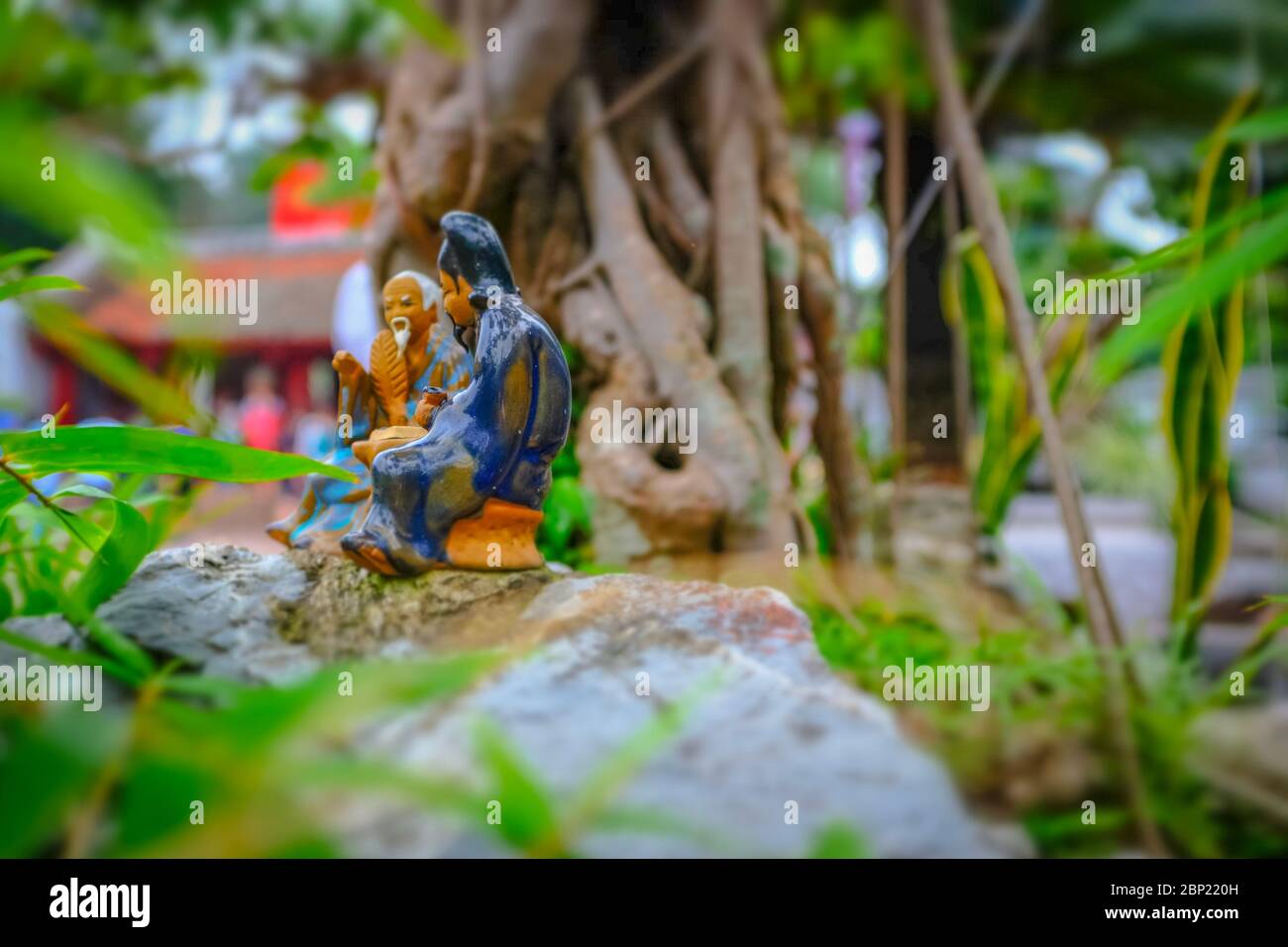 Petite figurine de deux hommes parlant portant des tissus traditionnels avec arrière et premier plan flous, Hanoi, Vietnam Banque D'Images