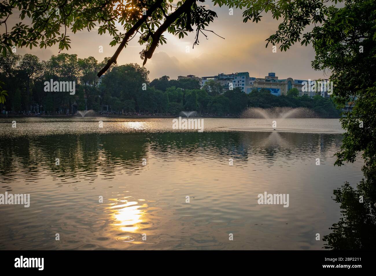 Lac Hoan Kiem au coucher du soleil, encadré de végétation, Hanoï, Vietnam Banque D'Images