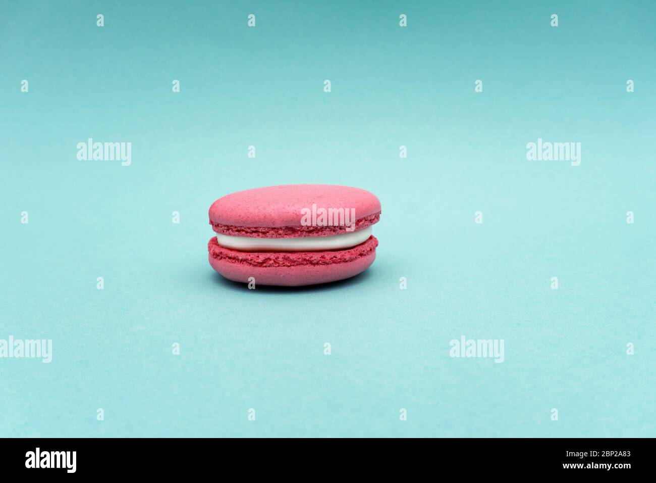 Macaron aux fraises roses sur fond menthe ou turquoise Banque D'Images