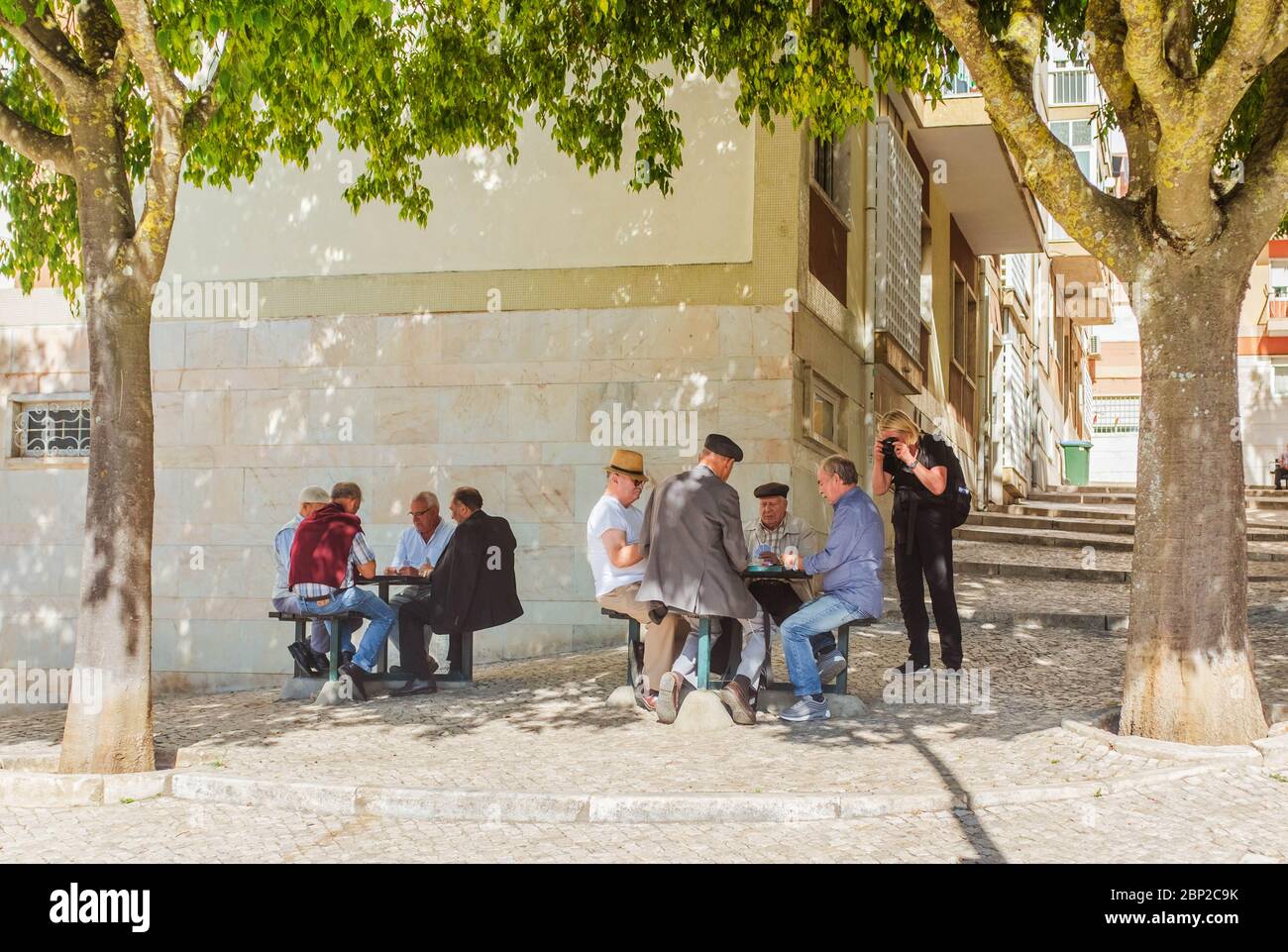 Femme touristique prenant des photos d'hommes portugais jouant des cartes à proximité de l'immeuble d'appartements. Banque D'Images