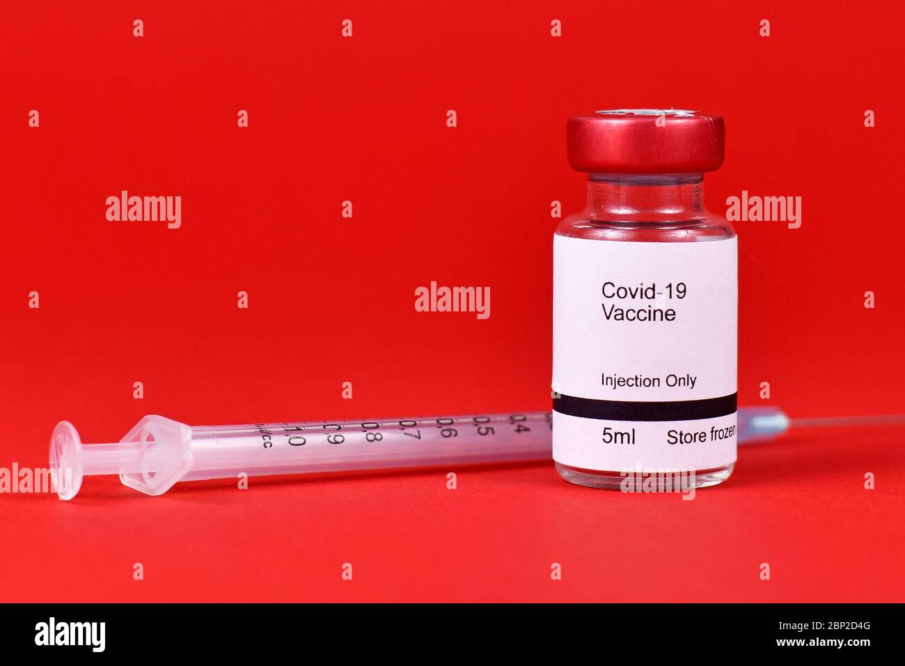 Vaccin contre le coronavirus concept avec petite bouteille avec texte « vaccin Covid-19 » avec seringue sur fond rouge flou Banque D'Images