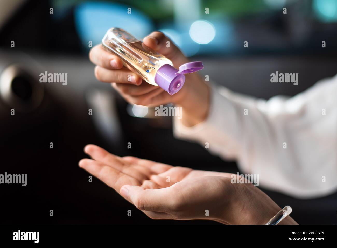 Femme utilisant un désinfectant pour les mains dans la voiture pour se désinfecter les mains à l'extérieur afin d'empêcher la propagation du virus pendant la pandémie Banque D'Images