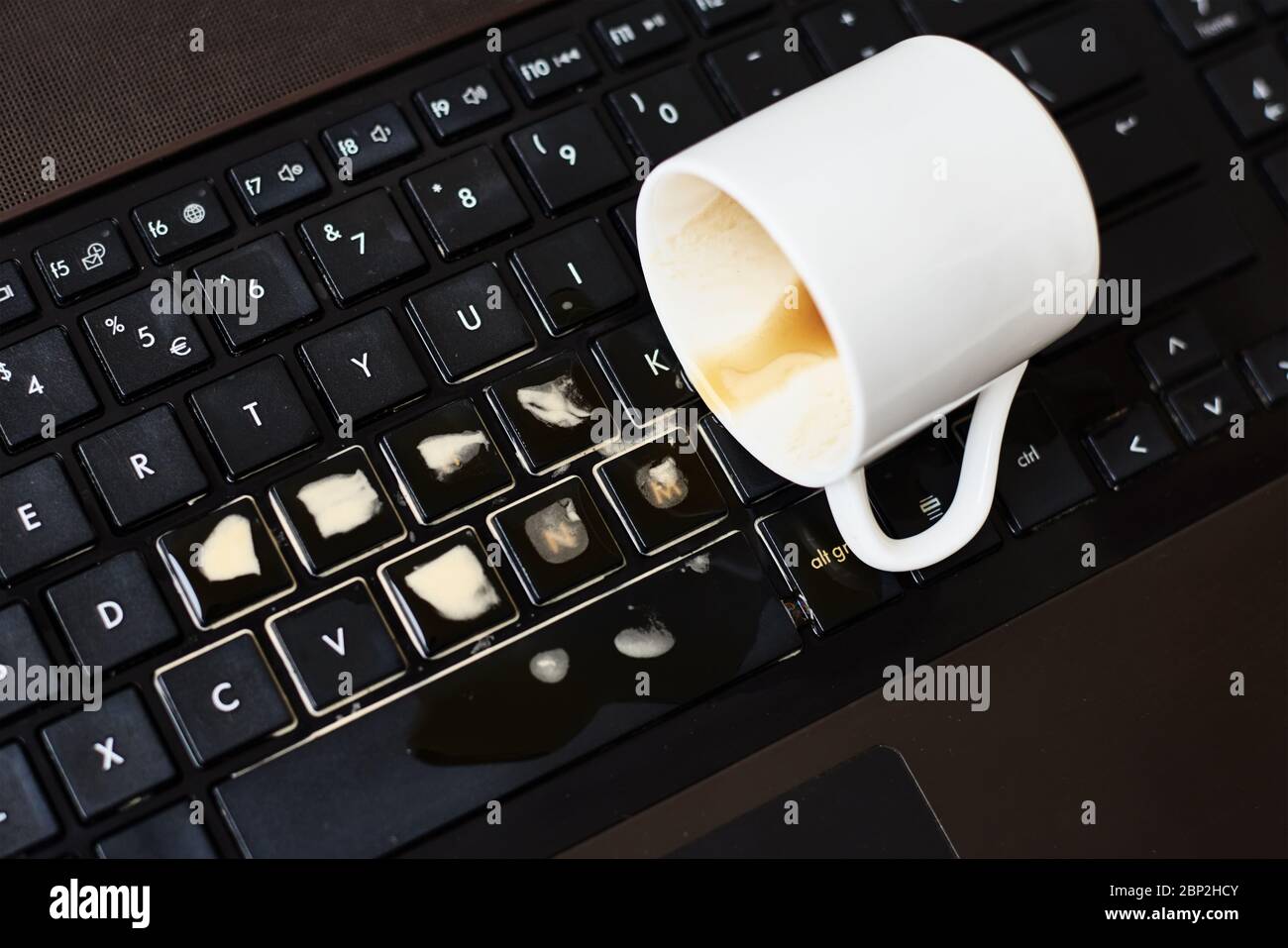 Renversez du café dans la tasse blanche sur le clavier de l'ordinateur portable. L'ordinateur est endommagé en raison d'un liquide renversé Banque D'Images Renversez du café dans la tasse blanche sur le clavier de l'ordinateur portable. L'ordinateur est endommagé en raison d'un liquide renversé Banque D'Images