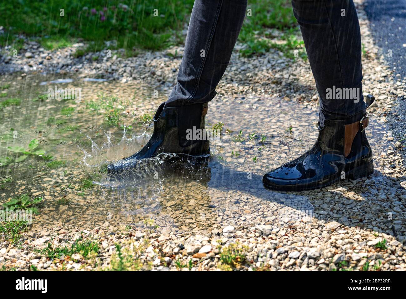 femme jouant dans une flaque de pluie intense avec des bottes de boursoufon Banque D'Images