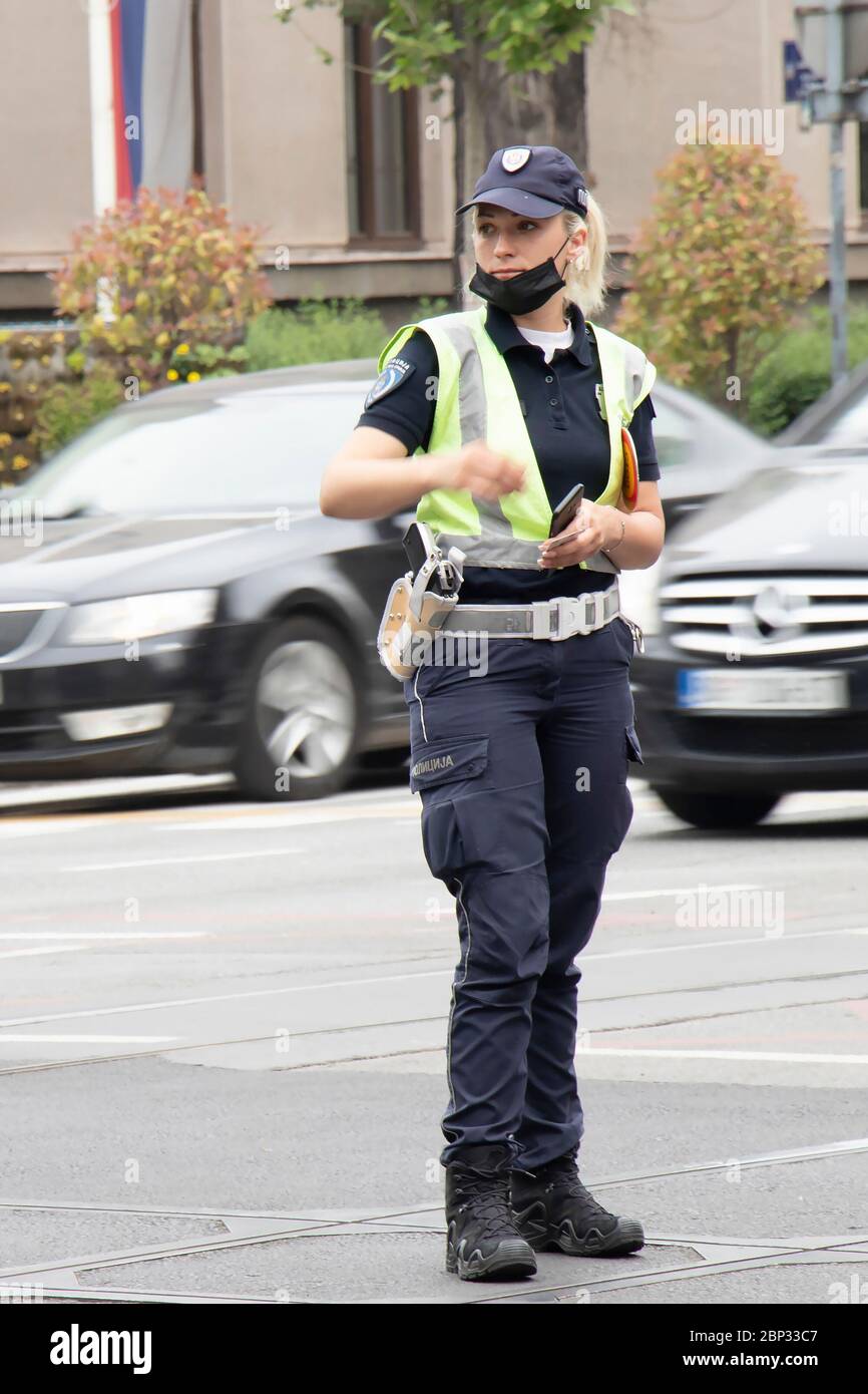 Belgrade, Serbie - 15 mai 2020 : policier de la circulation en service, debout à l'intersection, tandis que les véhicules se déplacent en mouvement s'estompent Banque D'Images