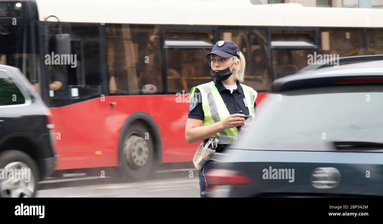 Belgrade, Serbie - 15 mai 2020 : policier de la circulation en service, debout à l'intersection, tandis que les véhicules se déplacent en mouvement s'estompent Banque D'Images