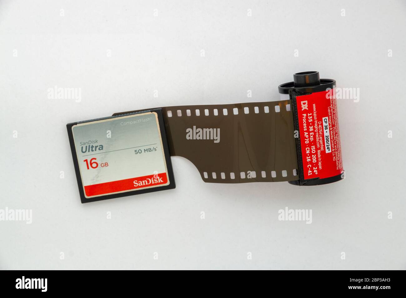 Vue en hauteur d'une carte SD de 16 Go à côté d'une cassette de film 35 mm légèrement non enroulée Banque D'Images