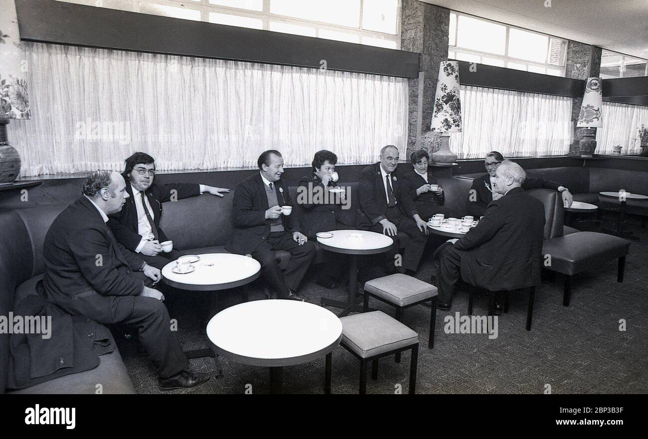 Photo intérieure montrant des ouvriers en autobus en uniforme assis dans une salle de repos au dépôt de bus de New Cross, sud-est de Londres, Angleterre, 1974. L'équipe d'autobus fait une pause, une tasse de thé, une fumée et une discussion avec des collègues de travail. D'origine un dépôt de tram, New Cross a été converti en un dépoet de bus n 1952 et était l'un des plus grands garages de Londres. Banque D'Images