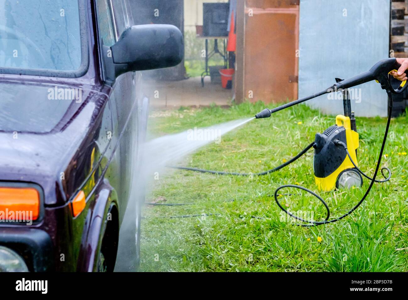 Lavage de voiture dans l'après-midi à l'extérieur avec un appareil haute  pression. Un puissant jet d'eau qui délasse la saleté du corps violet de la  voiture Photo Stock - Alamy