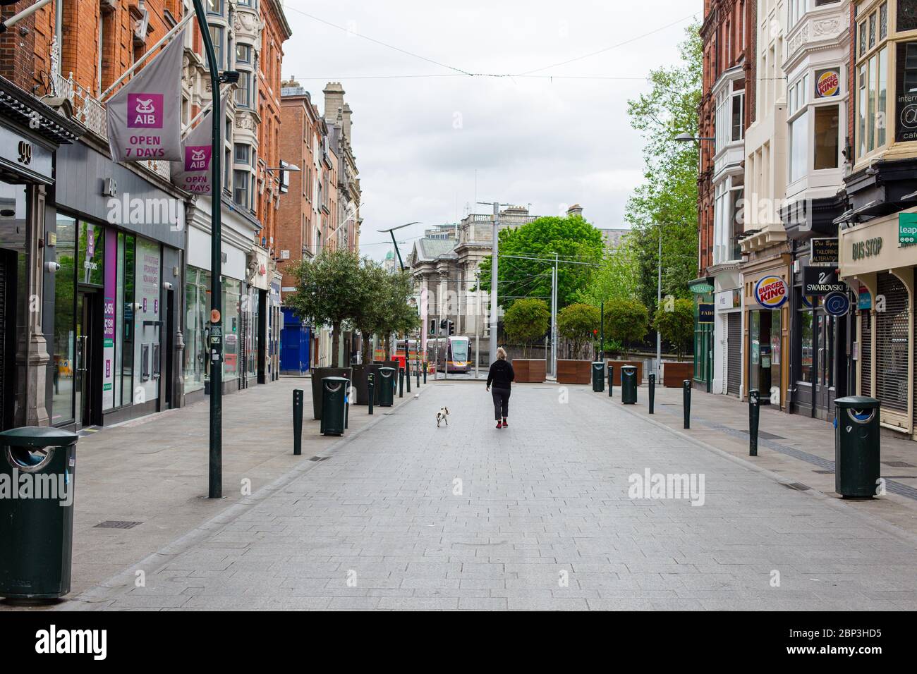 Des piétons se balader dans une rue Grafton déserte du centre-ville de Dublin alors que les magasins restent fermés en raison de restrictions liées à une pandémie de coronavirus. Banque D'Images