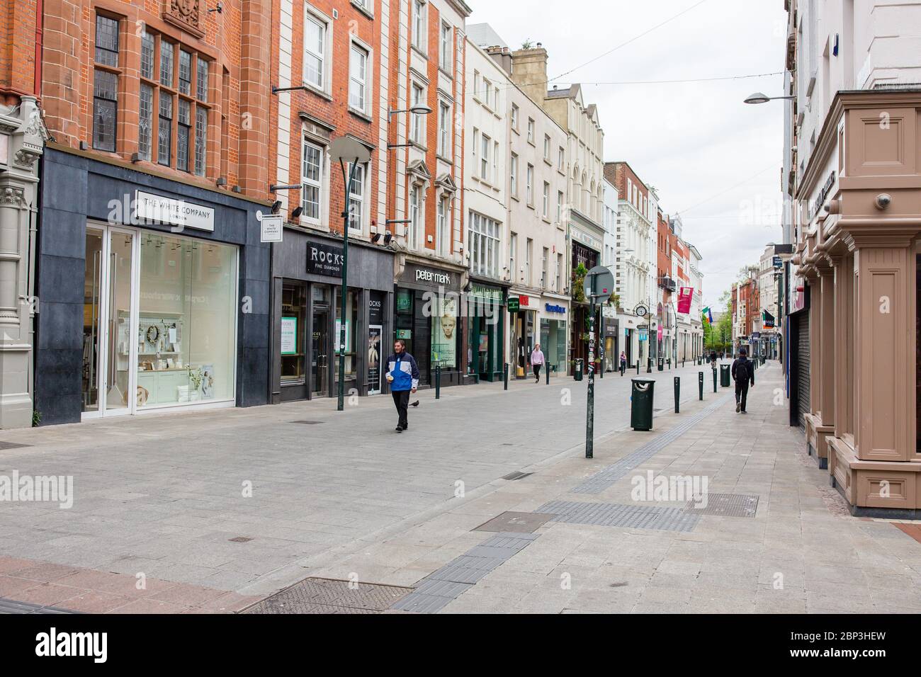 Des piétons se balader dans une rue Grafton déserte du centre-ville de Dublin alors que les magasins restent fermés en raison de restrictions liées à une pandémie de coronavirus. Banque D'Images