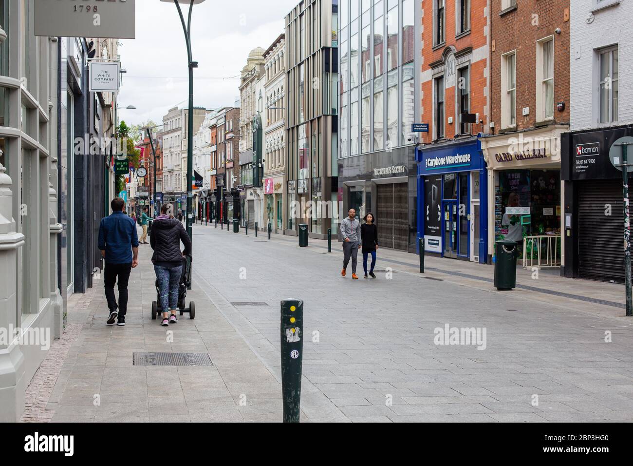 Des piétons se balader dans une rue Grafton déserte du centre-ville de Dublin alors que les magasins restent fermés en raison de restrictions liées à une pandémie de coronavirus. Banque D'Images