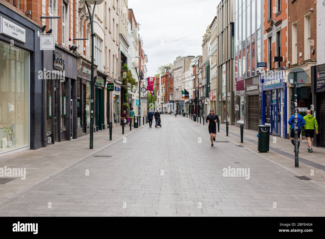 Des piétons se balader dans une rue Grafton déserte du centre-ville de Dublin alors que les magasins restent fermés en raison de restrictions liées à une pandémie de coronavirus. Banque D'Images