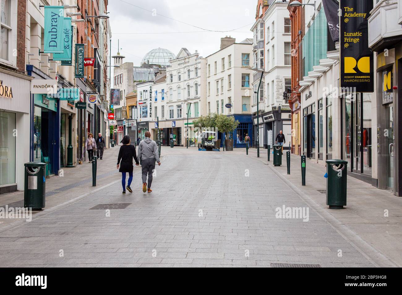 Des piétons se balader dans une rue Grafton déserte du centre-ville de Dublin alors que les magasins restent fermés en raison de restrictions liées à une pandémie de coronavirus. Banque D'Images