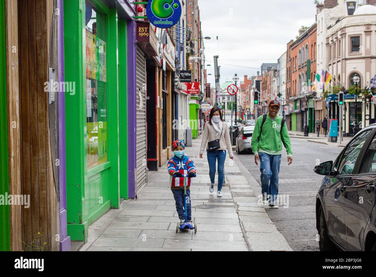 Garçon sur un scooter portant une veste de super-héros et un masque facial protecteur, qui visite ses parents au centre-ville de Dublin pendant la pandémie Covid-19 Banque D'Images