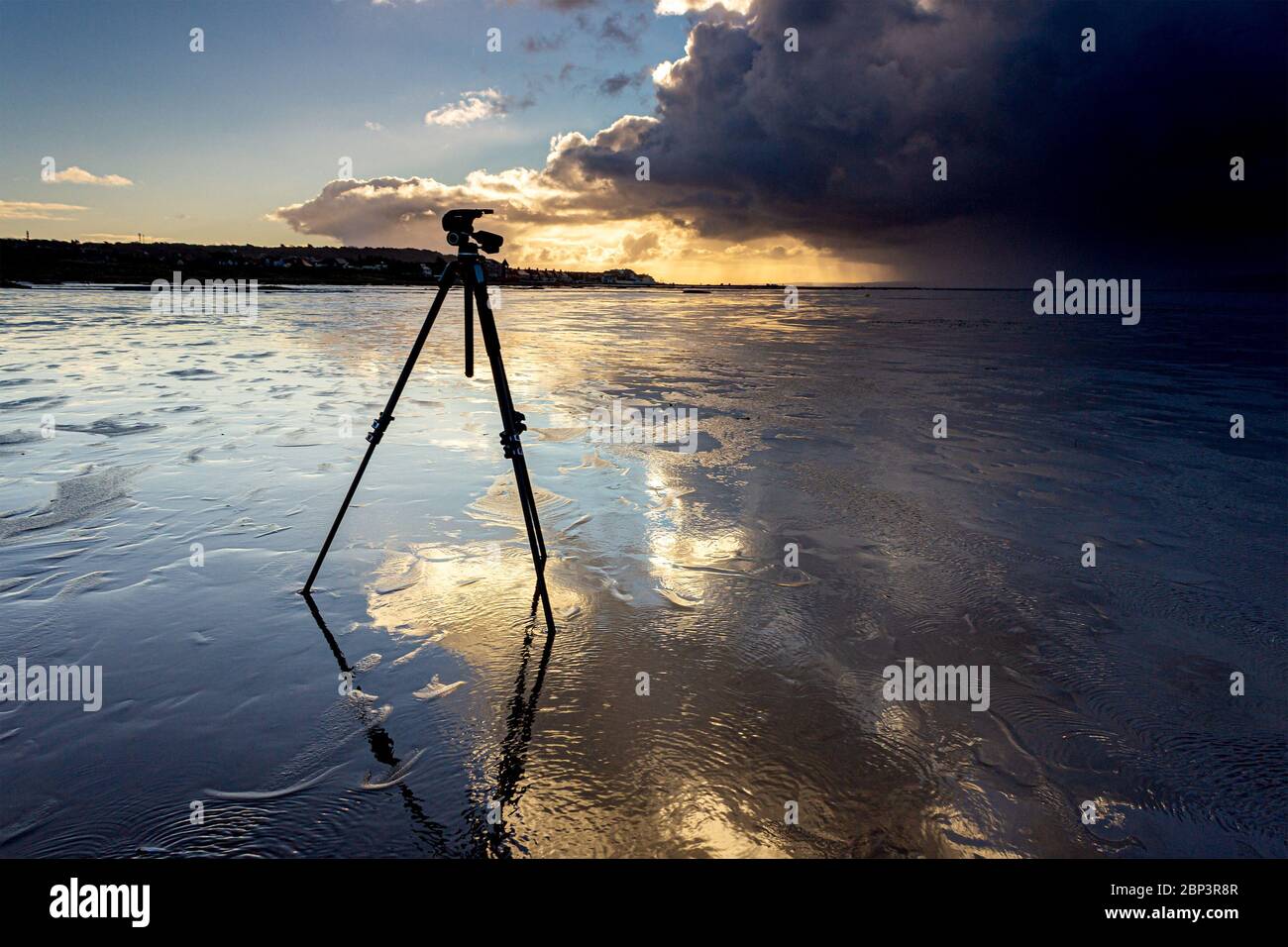 Trépied du photographe réfléchi sur la plage humide au lever du soleil, West Kirby, Wirral. Banque D'Images