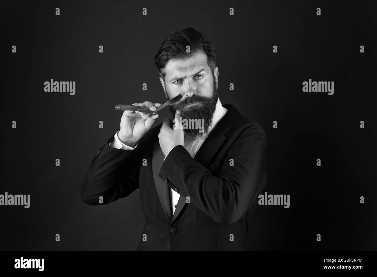 Intéressé par mes cheveux et ma barbe. Rasage du visage, l'homme barbu. Homme d'affaires Professionnel en salon de coiffure. Hipster avec moustache et barbe rasoir de rasage en attente. Un barbier. La coiffure. Banque D'Images