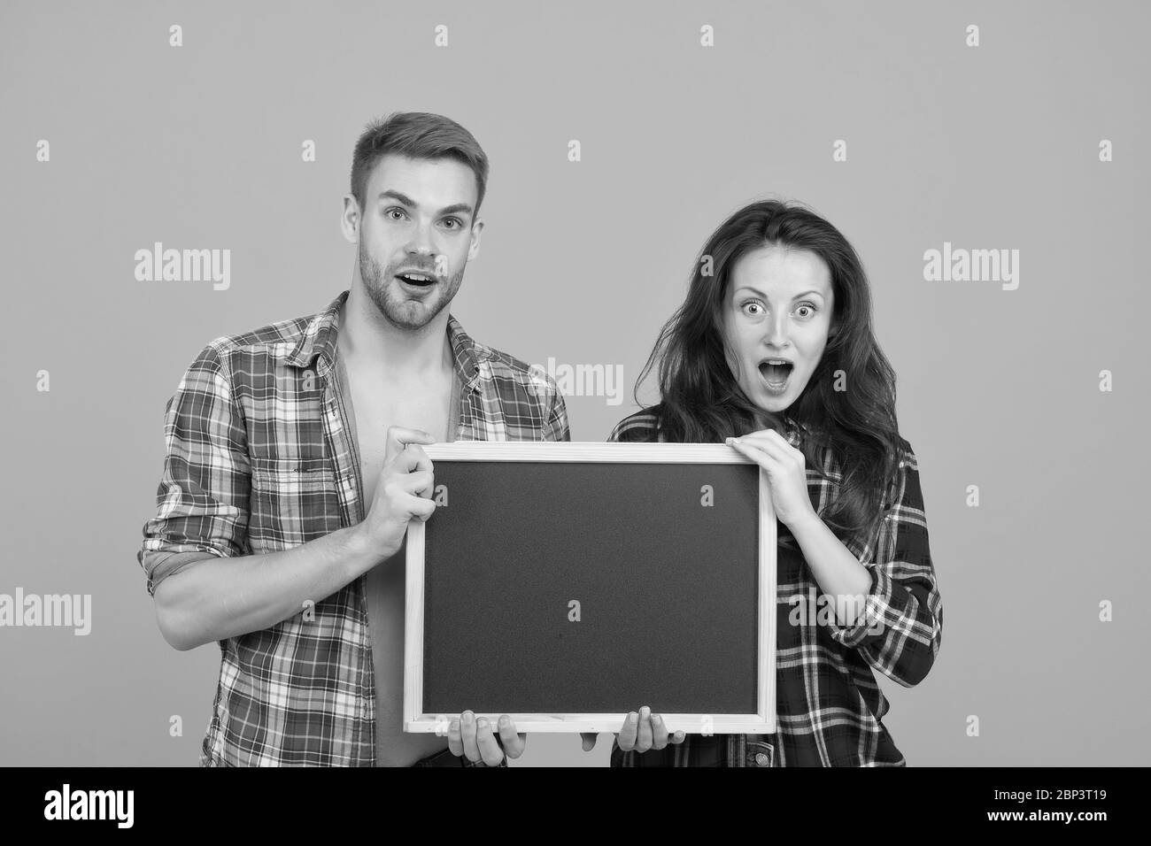 Couple avec tableau noir pour la publicité. Surpris couple jaune fond. Homme et femme publicité produits. Informations sur les réductions. Vente finale. C'est une grande surprise. Vraiment bonne nouvelle. Banque D'Images