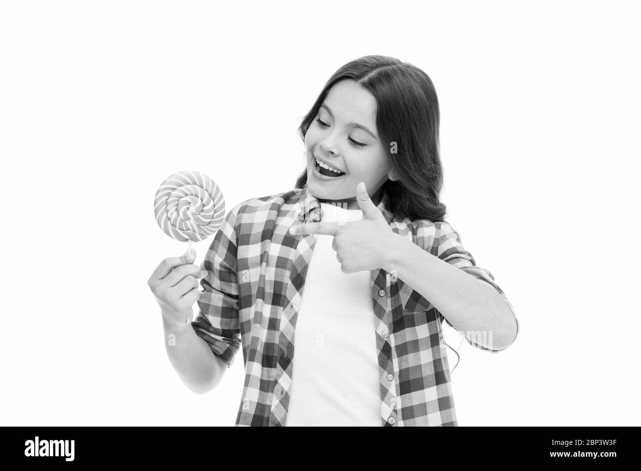 Regarde ça. Petite fille point à des bonbons isolés sur blanc. Petit enfant sourire avec des bonbons durs sur le bâton. Boutique de bonbons. Bonbons faits pour moi. Lollipop fait plaisir à elle. Banque D'Images