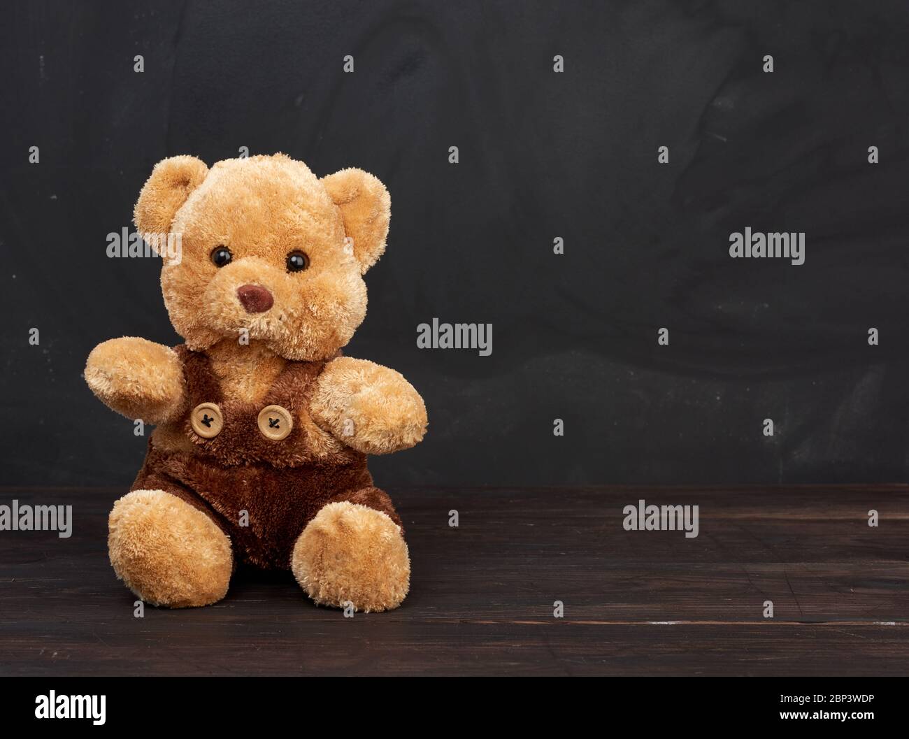 l'ours en peluche brun est assis sur une table en bois brun, derrière un tableau noir vide, place pour une inscription, retour à l'école Banque D'Images