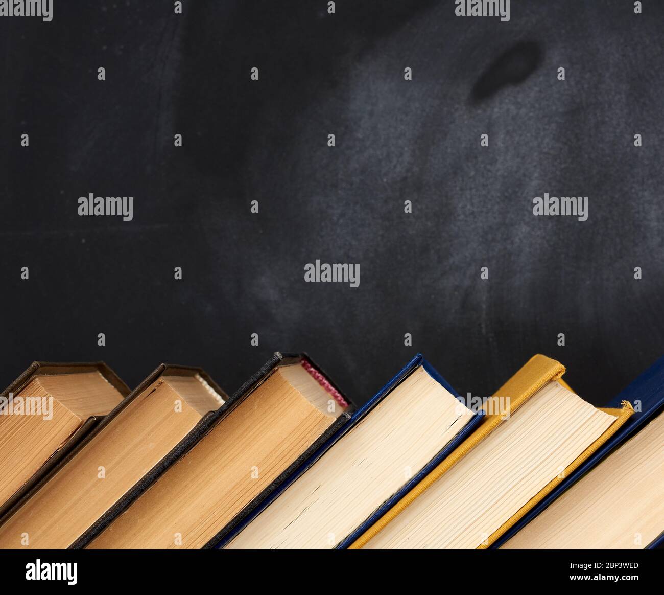 pile de divers livres sur le fond d'un tableau noir vide de craie, place pour le texte, retour à l'école Banque D'Images