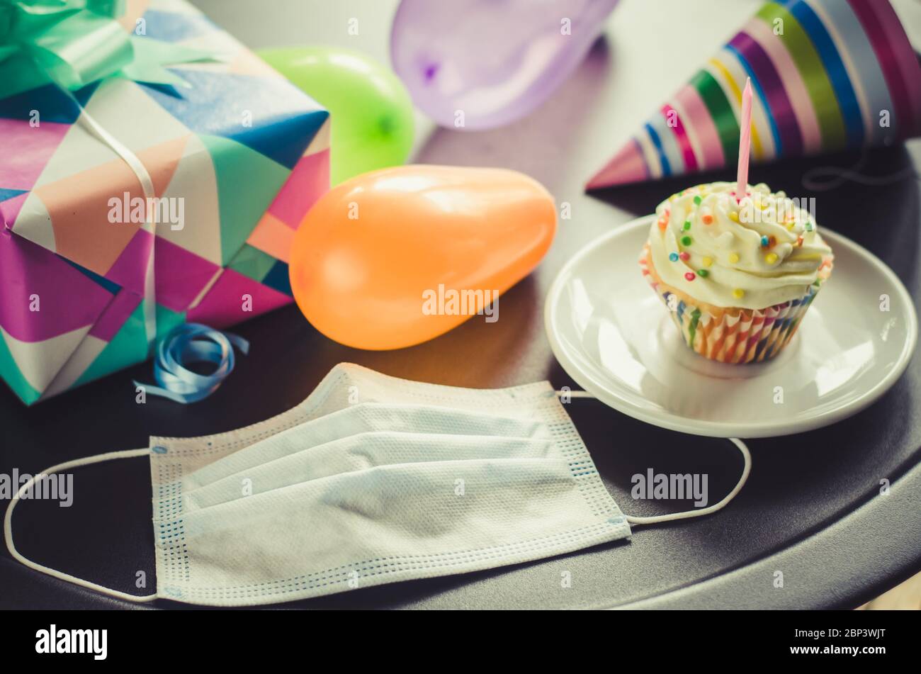 Mettre en quarantaine l'anniversaire en isolement. Gâteau d'anniversaire avec bougie, masque, cadeaux et accessoires de vacances. Distance sociale. Tonifier les images Banque D'Images