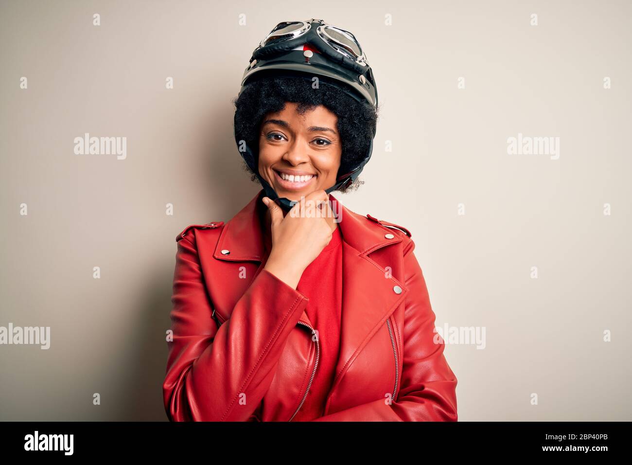 Jeune afro-américaine afro-motard femme avec cheveux bouclés portant un casque  moto regardant avec confiance la caméra souriant avec les bras croisés et  Photo Stock - Alamy