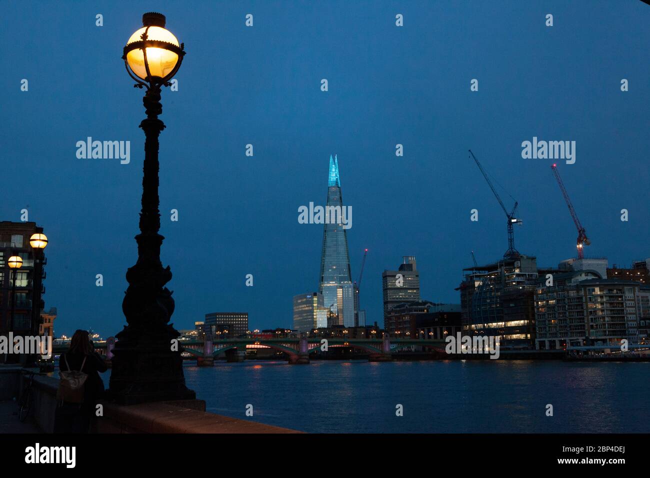 Londres, Royaume-Uni, 17 mai 2020 : une femme prend une photo du Shard, illuminé en bleu pour honorer le personnel du NHS et les autres travailleurs de soins et les principaux travailleurs de première ligne. Anna Watson/Alay Live News Banque D'Images