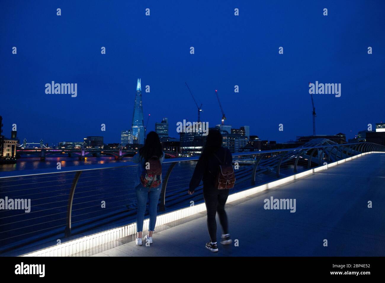 Londres, Royaume-Uni, 17 mai 2020 : les gens traversent le pont de Milemmium et le sommet du Shard est éclairé en bleu. Tate Modern est également doté d'une signalisation indiquant « Merci aux principaux employés » pour honorer le personnel du NHS et les autres travailleurs de soins et les principaux employés de première ligne. Anna Watson/Alay Live News Banque D'Images