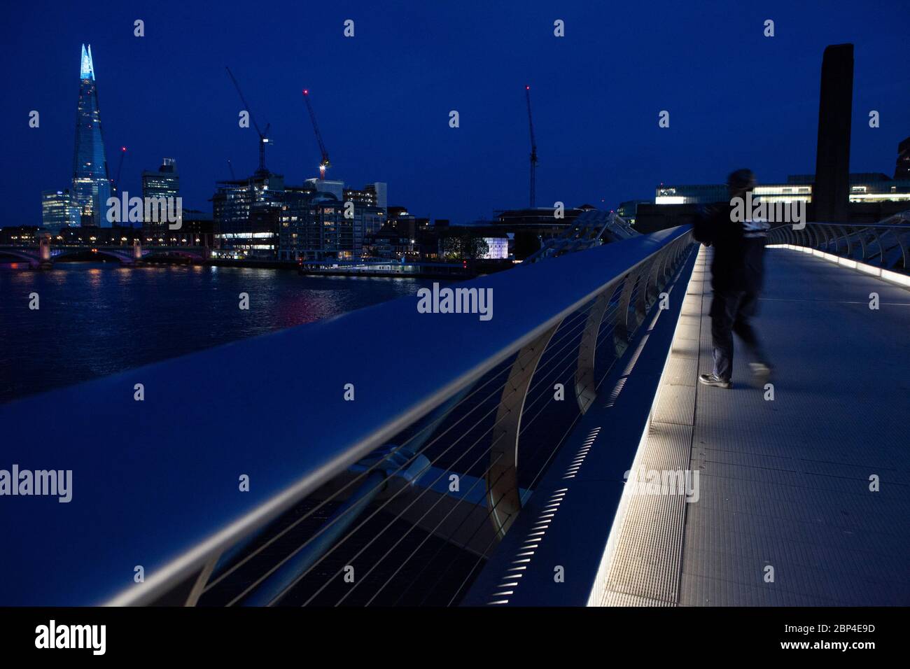 Londres, Royaume-Uni, 17 mai 2020 : les gens traversent le pont de Milemmium et le sommet du Shard est éclairé en bleu. Tate Modern est également doté d'une signalisation indiquant « Merci aux principaux employés » pour honorer le personnel du NHS et les autres travailleurs de soins et les principaux employés de première ligne. Anna Watson/Alay Live News Banque D'Images