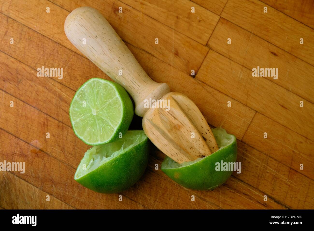 Limon juteux coupé en deux sur une planche à découper en bois avec un alésoir d'agrumes en bois; pressé ou alésé pour le jus. Banque D'Images