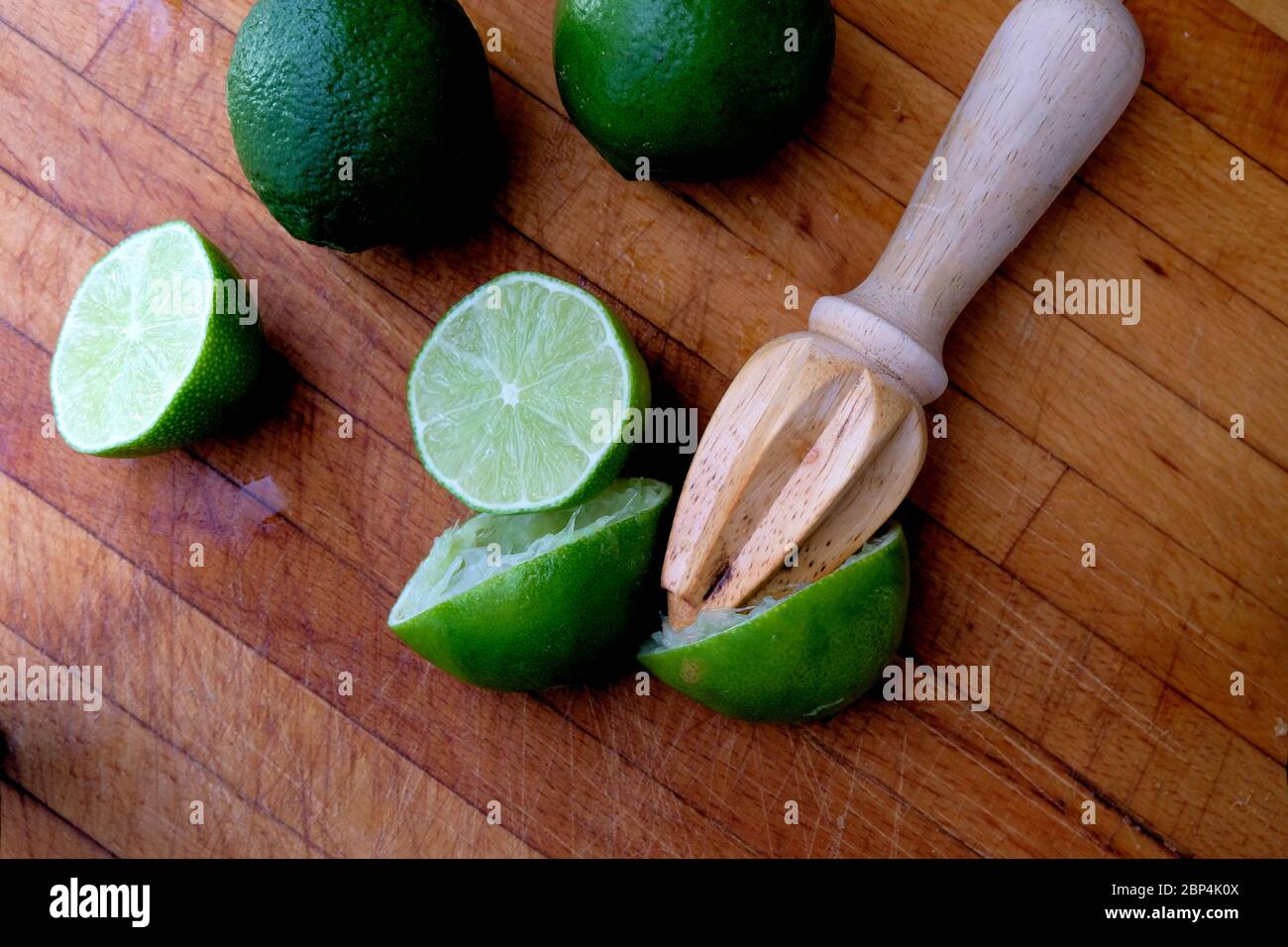 Limon juteux coupé en deux sur une planche à découper en bois avec un alésoir d'agrumes en bois; pressé ou alésé pour le jus. Banque D'Images