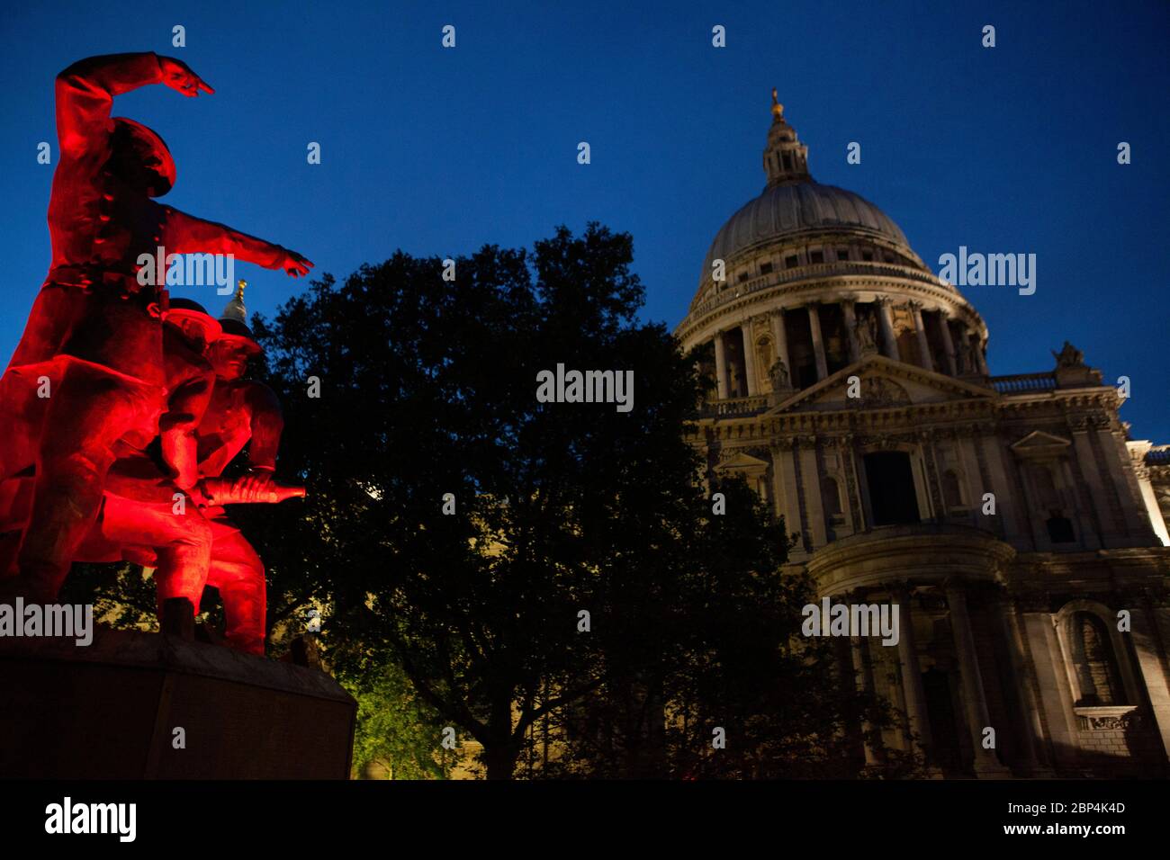 Le mémorial des pompiers, sur le côté sud de la cathédrale Saint-Paul, est éclairé par des lumières rouges clignotantes au crépuscule. Banque D'Images