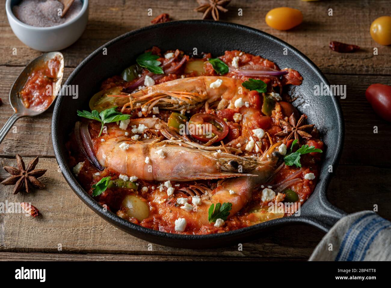 Crevettes cuites dans une poêle en fonte avec sauce tomate rouge, persil et feta. Banque D'Images
