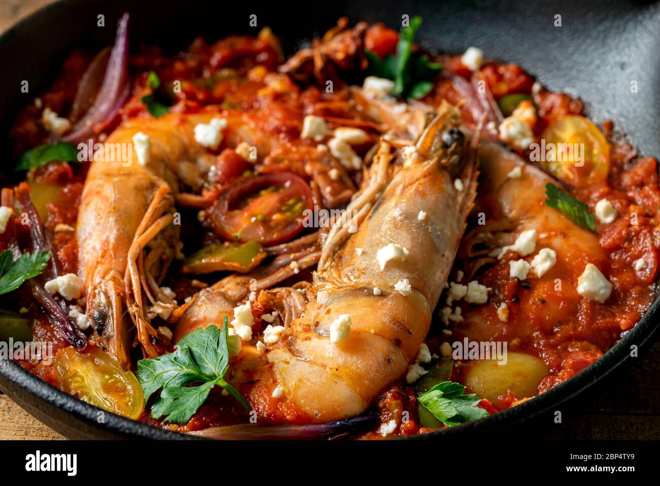 Crevettes cuites dans une poêle en fonte avec sauce tomate rouge, persil et  feta Photo Stock - Alamy
